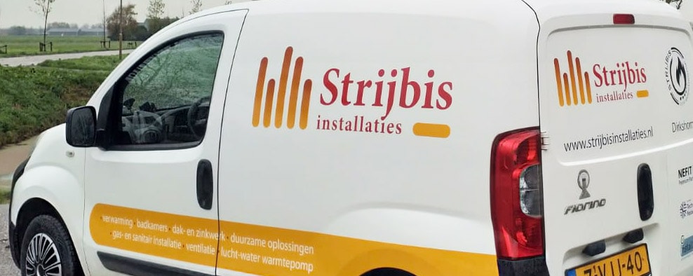 Een witte bestelauto met "Strijbis Installaties" autobelettering, een logo en contactgegevens staat geparkeerd in een landelijk gebied bij een weg. De zijkant en achterkant van de bestelauto zijn zichtbaar.